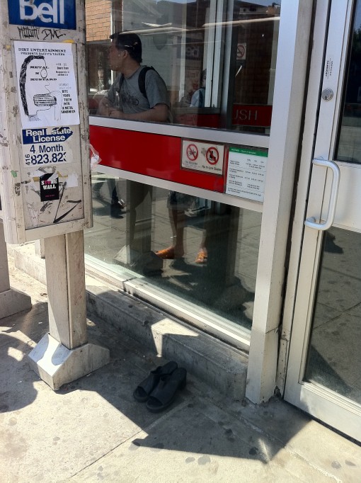shoes near the door of the entrance to a busy Toronto subway station